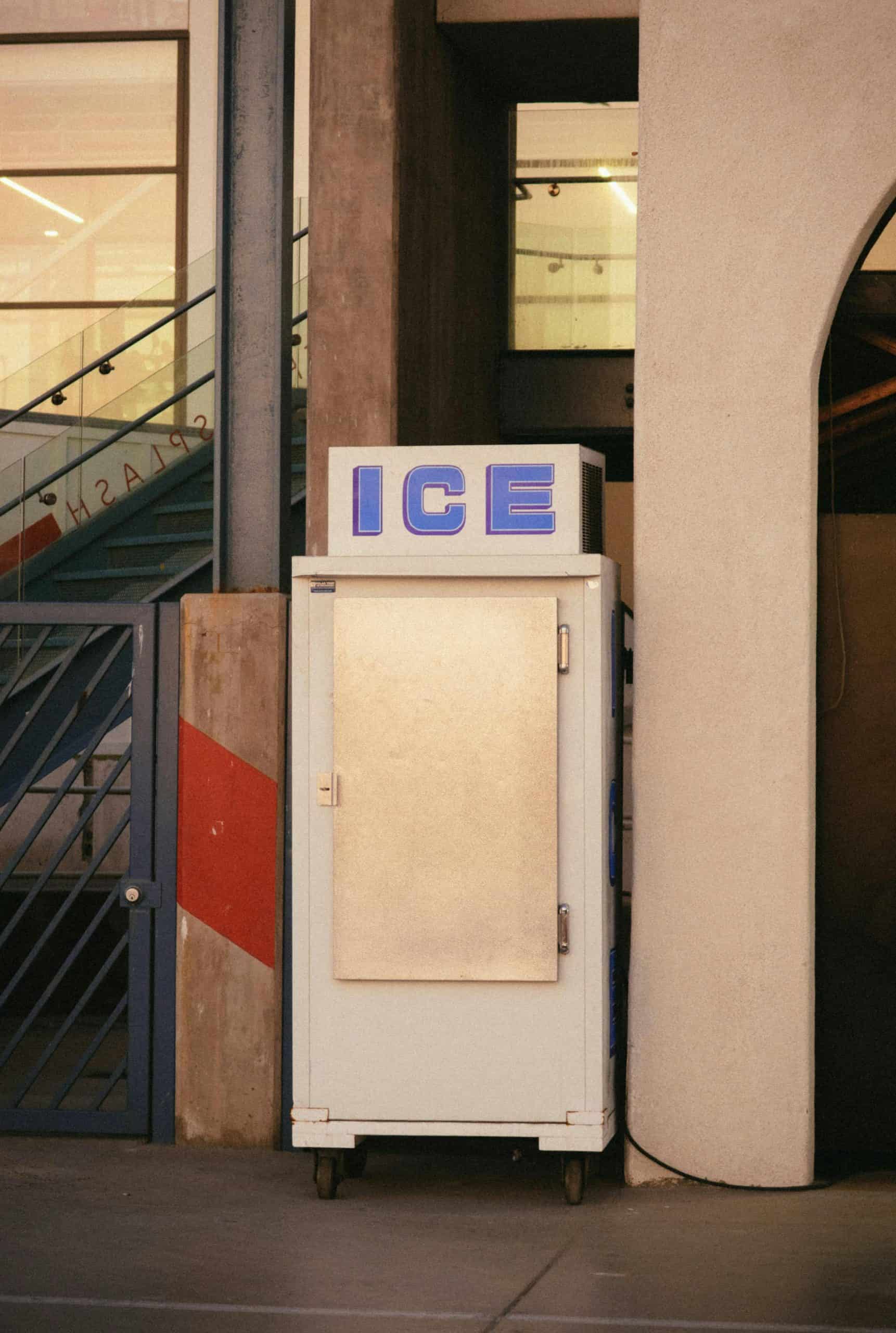 A vintage ice machine located outdoors on an urban sidewalk, showcasing retro design.