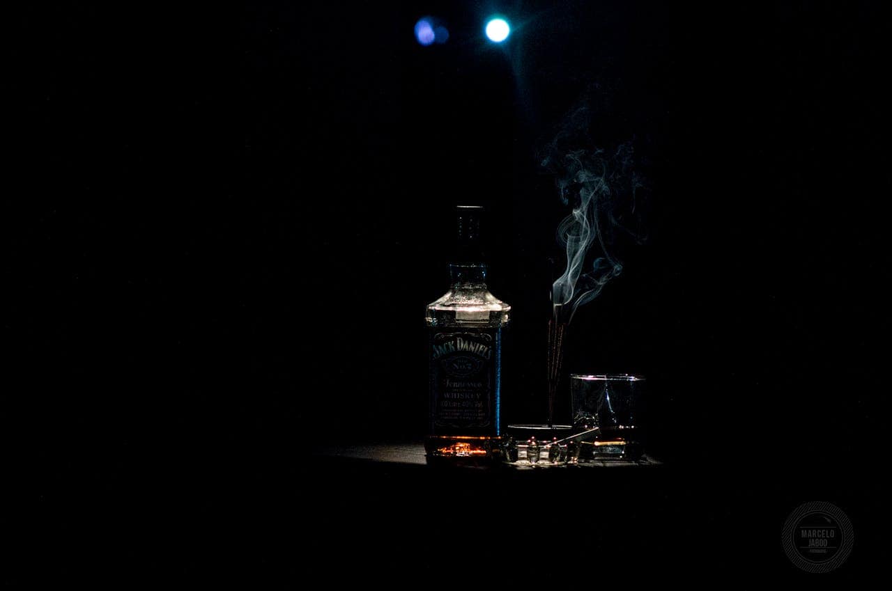 A dramatic whiskey bottle with smoke on a dark background, accented by soft lighting.